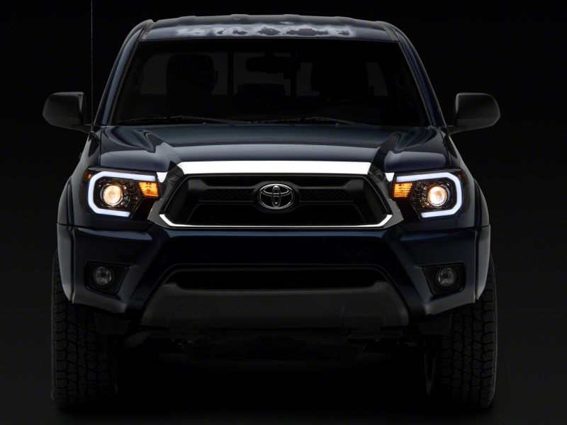 Raxiom 12-15 Toyota Tacoma Axial Projector Headlights w/ SEQL LED Bar- Black Housing (Clear Lens) Headlights Raxiom