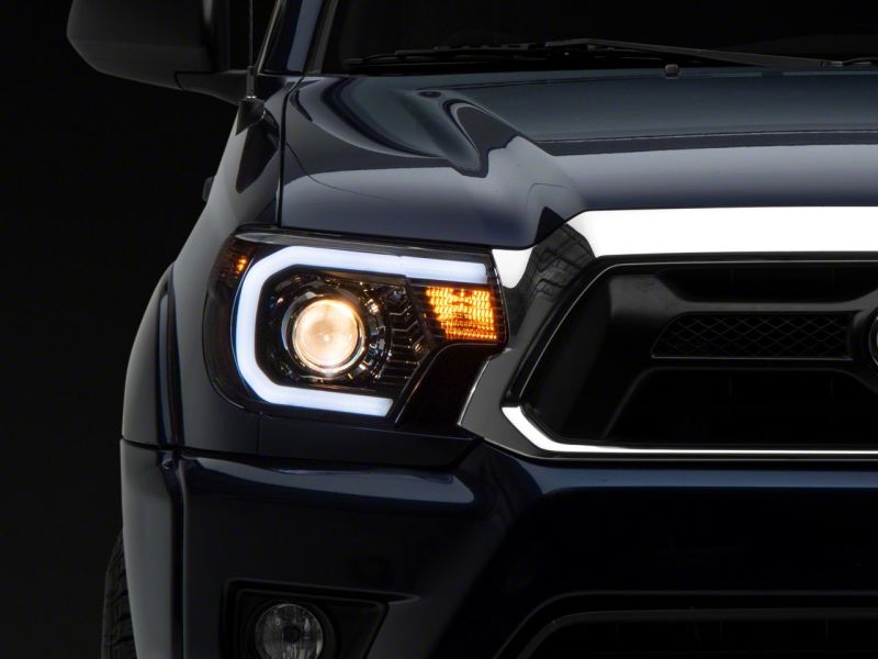 Raxiom 12-15 Toyota Tacoma Axial Projector Headlights w/ SEQL LED Bar- Black Housing (Clear Lens) Headlights Raxiom